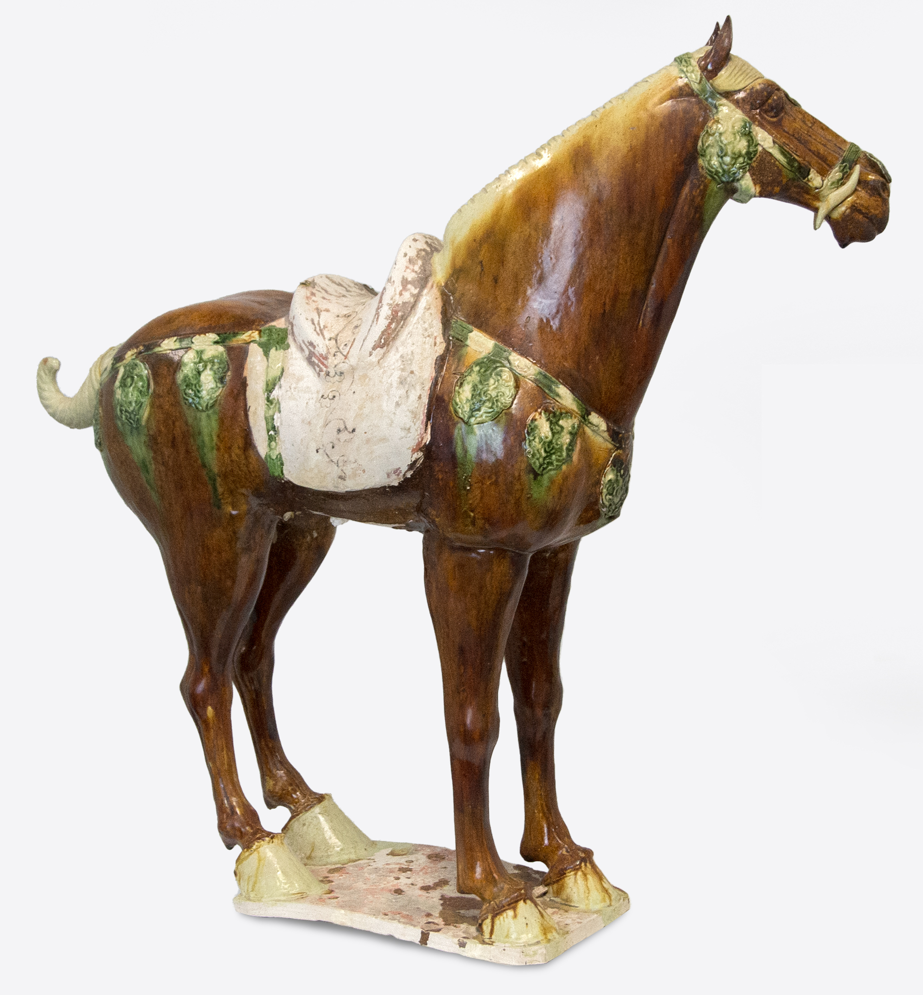 CHINESE - Sancai-Glazed Horse The Tang Dynasty (618-907 AD) was a prosperous period that helped shape Chinese history's foundations for future centuries. This era was marked by notable technological and cultural advances, including gunpowder and printing. Among artistic advances during this period was the perfection of the sancai glaze technique, which was a prominent attribute of sculpture during this period. Sancai (tri-colored) glazing used the three glaze-colors were ochre or brown, green and clear. Glazed wares were much more costly to produce than other terracotta wares, and were therefore only reserved for the wealthiest patrons. <br><br>This Sancai-Glazed Horse would have been an incredible status symbol for its owner and many have been lost to time. This sculpture is comparable to examples held in museum collections worldwide, including the Metropolitan Museum of Art, New York.
