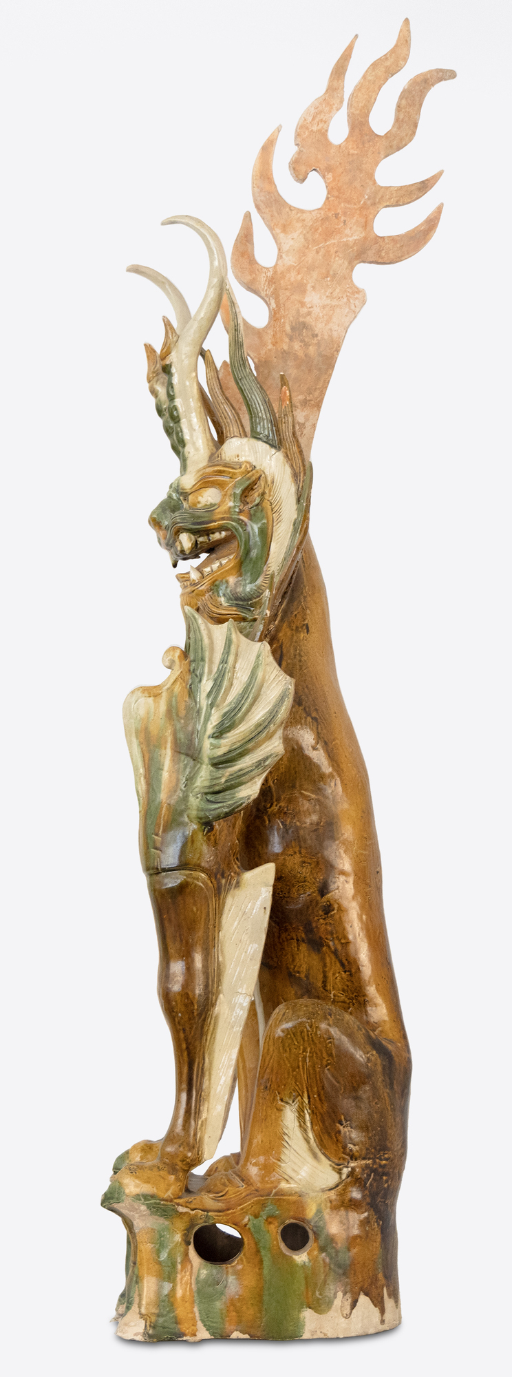 CHINESE - Sancai-Glazed Earth Spirit The Tang Dynasty (618-907 AD) was a prosperous cultural period that helped shape Chinese history's foundations for future centuries. This era was marked by notable technological and cultural advances, including gunpowder and printing. Among artistic advances during this period was the perfection of the sancai glaze technique, which was a prominent attribute of sculpture during this period. Sancai (tri-colored) glazing; the three glaze-colors used were ochre or brown, green and clear. Glazed wares where much more costly to produce than other terracotta wares, and were therefore only reserved for the wealthiest patrons.
<br>
<br>The Sancai-Glazed Earth Spirit offered here depicts a "Zhenmushou." These are mythical hybrid creatures whose bodies are a combination of dogs, lions, boars and other animals. These fierce looking beasts would be found in pairs guarding the entrance of Tang Dynasty tombs.