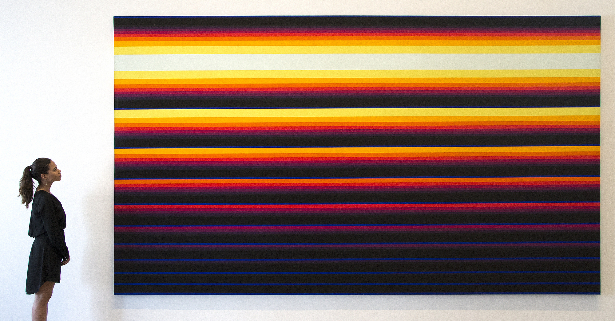 NORMAN ZAMMITT - North Wall North Wall was exhibited at the Getty Museum in the Pacific Standard Time exhibition tracing the history of art in L.A. from 1945 to 1980, which reignited interest in Light and Space and brought fresh eyes to the work of Norman Zammitt. For this piece, the artist measured the width of each band and created parabolic graphs to calculate the exacting color progression — not only for aesthetic precision, but also for emotional and spiritual effect. The colors seem to radiate as they shift from dark bands of black and blue to fiery yellows, oranges and reds. The hard edges of these bands bring to mind the school of L.A. artists who worked in geometric abstraction during the same period, predominantly the 1960s and ’70s, particularly Karl Benjamin's classic stripe paintings. But Zammitt’s ethereal pictures defy any such classification. His edges appear seamless — a moment in space frozen in time. The expanse evokes a sky in its full coastal California drama, although that was not necessarily the artist’s intention. Rather, he might have used these as an approach to the sublime — portal to a mystical realm. His late, longtime dealer, Joni Gordon of Newspace, suggested the exacting bands of brilliant color relate to Native Indian sand paintings.