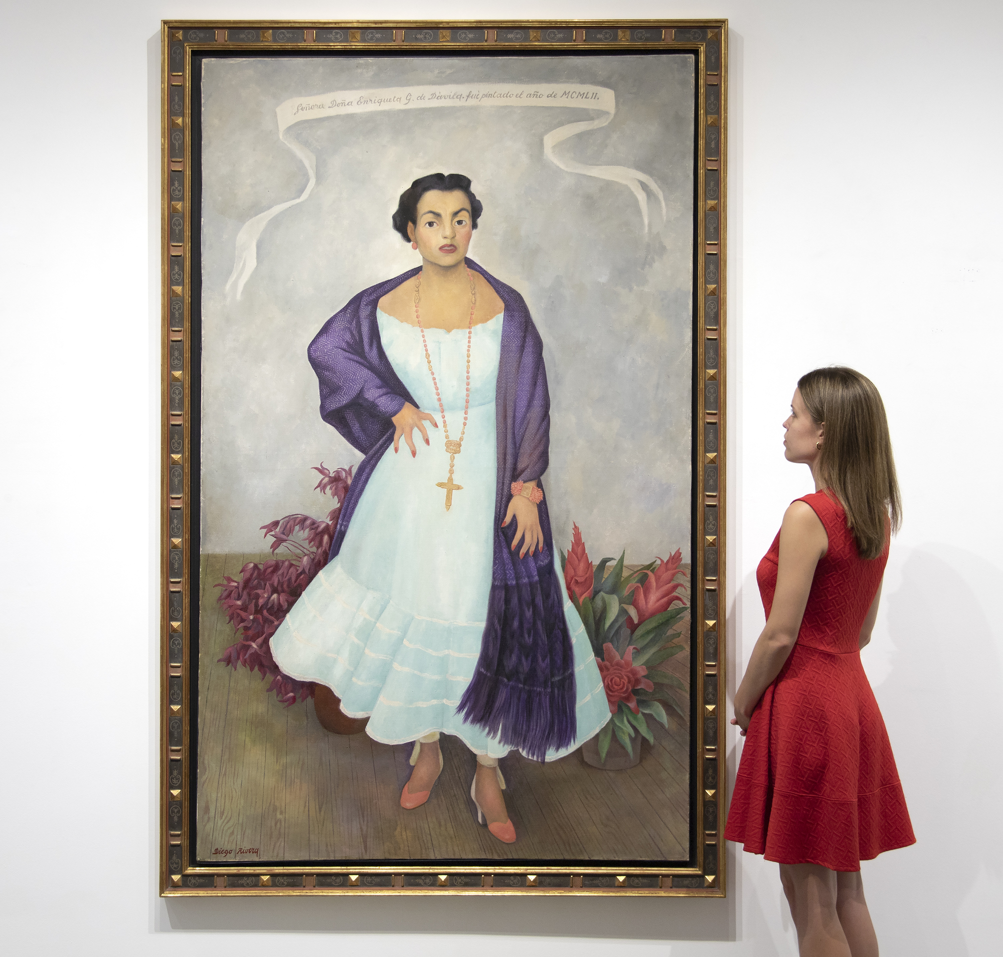 &lt;br&gt;In Diego Rivera’s portrait of Enriqueta Dávila, the artist asserts a Mexicanidad, a quality of Mexican-ness, in the work along with his strong feelings towards the sitter. Moreover, this painting is unique amongst his portraiture in its use of symbolism, giving us a strong if opaque picture of the relationship between artist and sitter.&lt;br&gt;&lt;br&gt;Enriqueta, a descendent of the prominent Goldbaum family, was married to the theater entrepreneur, José María Dávila. The two were close friends with Rivera, and the artist initially requested to paint Enriqueta’s portrait. Enriqueta found the request unconventional and relented on the condition that Rivera paints her daughter, Enriqueta “Quetita”. Rivera captures the spirit of the mother through the use of duality in different sections of the painting, from the floorboards to her hands, and even the flowers. Why the split in the horizon of the floorboard? Why the prominent cross while Enriqueta’s family is Jewish? Even her pose is interesting, showcasing a woman in control of her own power, highlighted by her hand on her hip which Rivera referred to as a claw, further complicating our understanding of her stature.&lt;br&gt;&lt;br&gt;This use of flowers, along with her “rebozo” or shawl, asserts a Mexican identity. Rivera was adept at including and centering flowers in his works which became a kind of signature device. The flowers show bromeliads and roselles; the former is epiphytic and the latter known as flor de jamaica and often used in hibiscus tea and aguas frescas. There is a tension then between these two flowers, emphasizing the complicated relationship between Enriqueta and Rivera. On the one hand, Rivera demonstrates both his and the sitter’s Mexican identity despite the foreign root of Enriqueta’s family but there may be more pointed meaning revealing Rivera’s feelings to the subject. The flowers, as they often do in still life paintings, may also refer to the fleeting nature of life and beauty. The portrait for her daughter shares some similarities from the use of shawl and flowers, but through simple changes in gestures and type and placement of flowers, Rivera illuminates a stronger personality in Enriqueta and a more dynamic relationship as filtered through his lens.&lt;br&gt;&lt;br&gt;A closer examination of even her clothing reveals profound meaning. Instead of a dress more in line for a socialite, Rivera has Enriqueta in a regional dress from Jalisco, emphasizing both of their Mexican identities. On the other hand, her coral jewelry, repeated in the color of her shoes, hints at multiple meanings from foreignness and exoticism to protection and vitality. From Ancient Egypt to Classical Rome to today, coral has been used for jewelry and to have been believed to have properties both real and symbolic. Coral jewelry is seen in Renaissance paintings indicating the vitality and purity of woman or as a protective amulet for infants. It is also used as a reminder, when paired with the infant Jesus, of his future sacrifice. Diego’s use of coral recalls these Renaissance portraits, supported by the plain background of the painting and the ribbon indicating the maker and date similar to Old Master works.&lt;br&gt;&lt;br&gt;When combined in the portrait of Enriqueta, we get a layered and tense building of symbolism. Rivera both emphasizes her Mexican identity but also her foreign roots. He symbolizes her beauty and vitality but look closely at half of her face and it is as if Rivera has painted his own features onto hers. The richness of symbolism hints at the complex relationship between artist and sitter.