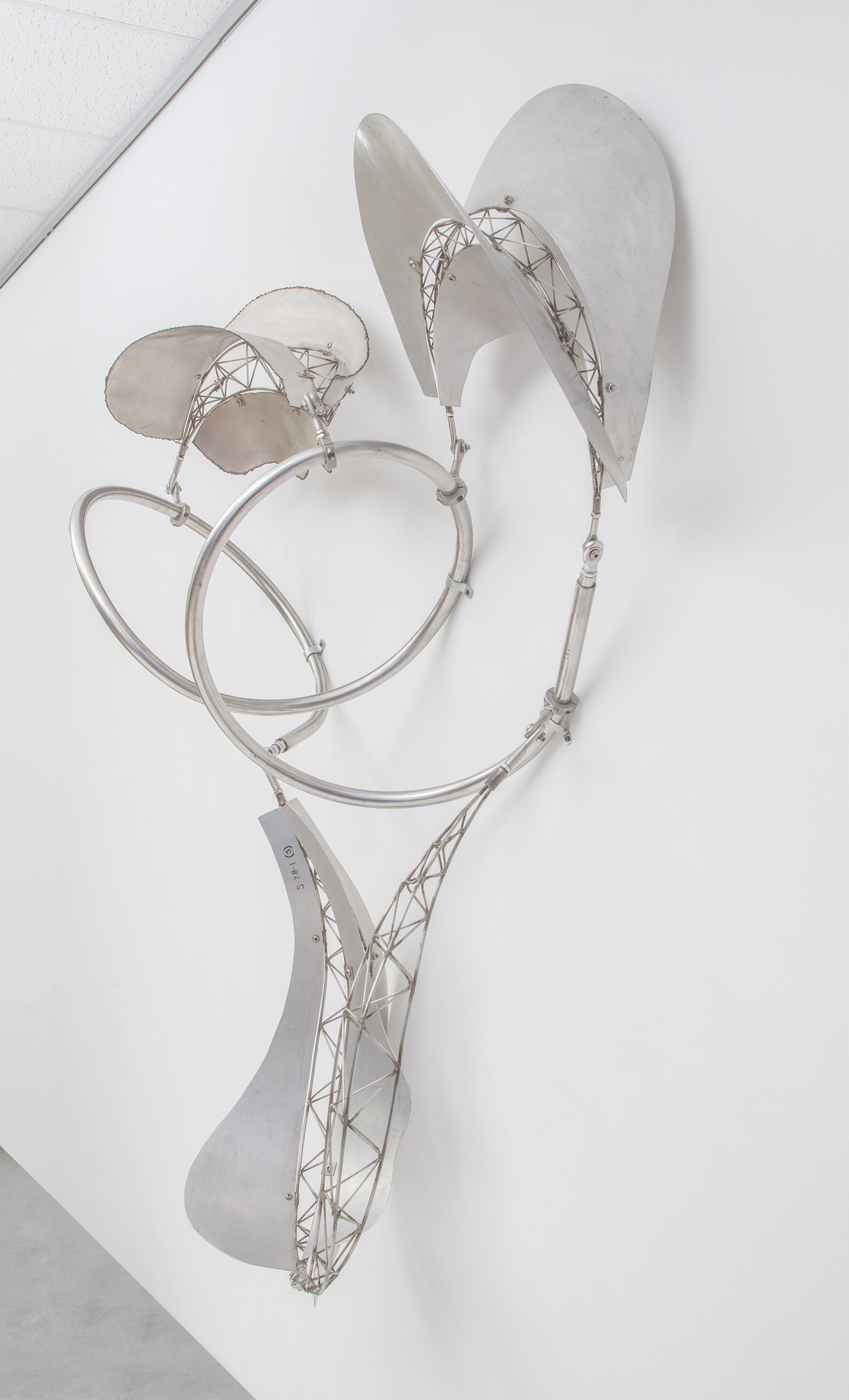La série de sculptures Bali de Frank Stella se caractérise par des formes flottantes et fluides, s’étendant dans l’espace du spectateur et invitant à l’interaction entre l’objet et son environnement. Le « dadap », un type d’arbre associé à la croissance et à la signification rituelle dans la culture balinaise, reflète la nature organique et dynamique des sculptures de Stella. En passant de l’acier inoxydable et de l’aluminium au bambou, Stella a préservé la nature essentielle de l’esthétique balinaise qui exalte des formes organiques, fluides et dynamiques dans leur espace. Dadap présente une continuité dans l’exploration thématique de Stella où l’esprit de son travail transcende la matérialité. Le métal offre une texture, une réflectivité et une interaction différentes avec la lumière et l’espace, tout en adhérant aux principes du mouvement et de l’interactivité. Il s’agit d’un transfert créatif de forme et de concept à travers différents médiums, en conservant l’esprit de l’inspiration initiale tout en permettant aux propriétés du nouveau matériau d’exprimer ces idées dans un nouveau contexte.