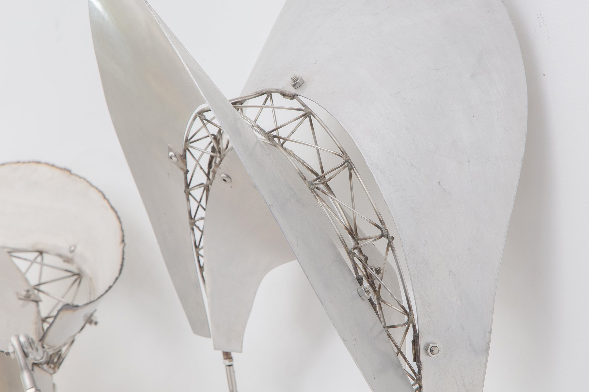 Frank Stellas Bali-Skulpturenserie zeichnet sich durch schwebende und fließende Formen aus, die sich in den Raum des Betrachters erstrecken und zur Interaktion zwischen dem Objekt und seiner Umgebung einladen. Der &quot;Dadap&quot;, eine Baumart, die in der balinesischen Kultur mit Wachstum und ritueller Bedeutung assoziiert wird, spiegelt die organische und dynamische Natur von Stellas Skulpturen wider. Mit dem Wechsel von Bambus zu Edelstahl und Aluminium hat Stella das Wesen der balinesischen Ästhetik bewahrt, die organische, fließende Formen preist, die sich dynamisch mit ihrem Raum verbinden. Dadap stellt eine Kontinuität in Stellas thematischer Erkundung dar, bei der der Geist seiner Arbeit über die Materialität hinausgeht. Metall bietet eine andere Textur, ein anderes Reflexionsvermögen und eine andere Interaktion mit Licht und Raum, hält aber dennoch an den Prinzipien von Bewegung und Interaktivität fest. Es handelt sich um eine kreative Übertragung von Form und Konzept über verschiedene Medien hinweg, wobei der Geist der ursprünglichen Inspiration beibehalten wird, während die Eigenschaften des neuen Materials diese Ideen in einem neuen Kontext zum Ausdruck bringen können.